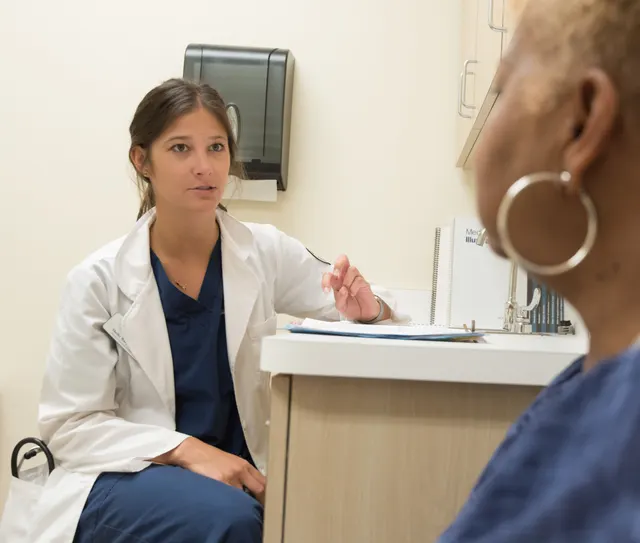 A clinician in a white coat talking with a patient