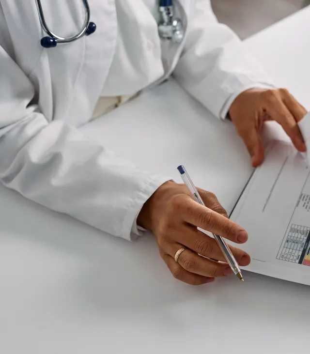 A clinician in a white coat reviewing a printed medical report