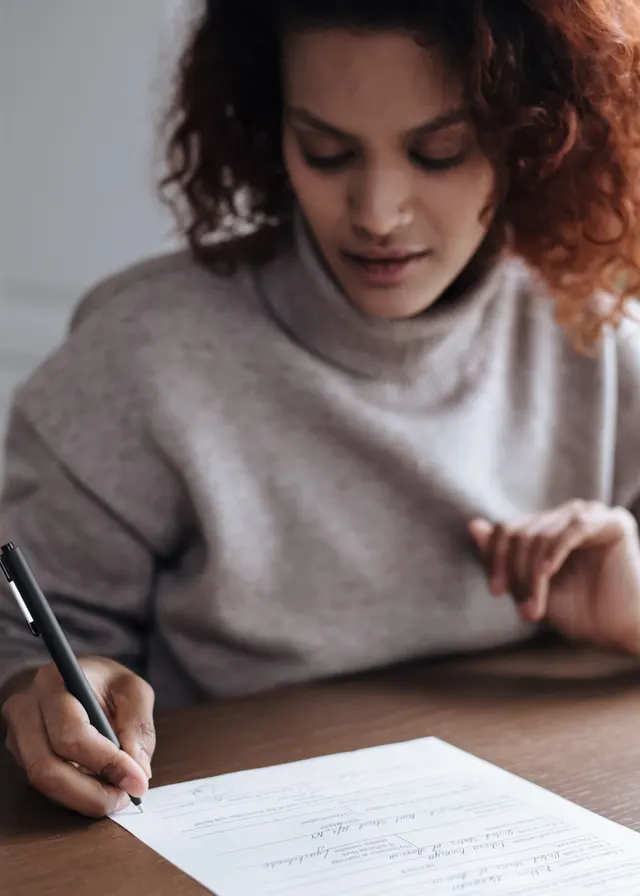 A person filling out a paper form with a pen